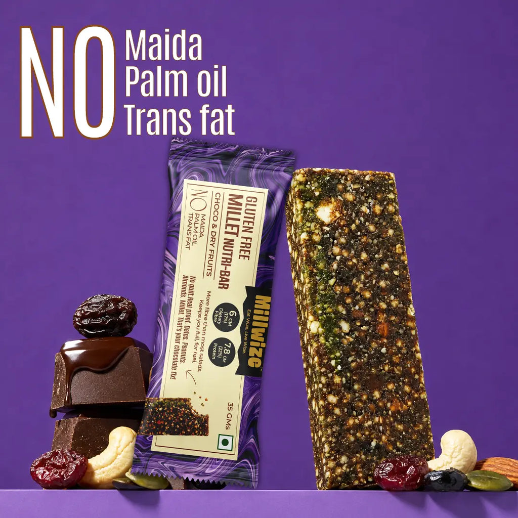 A packaged gluten free millet nut bar stands next to a loose, textured nut bar on a purple background, with stacked chocolate and dried fruit pieces at the base. Large text at the top reads 'NO Maida Palm oil Trans fat'.