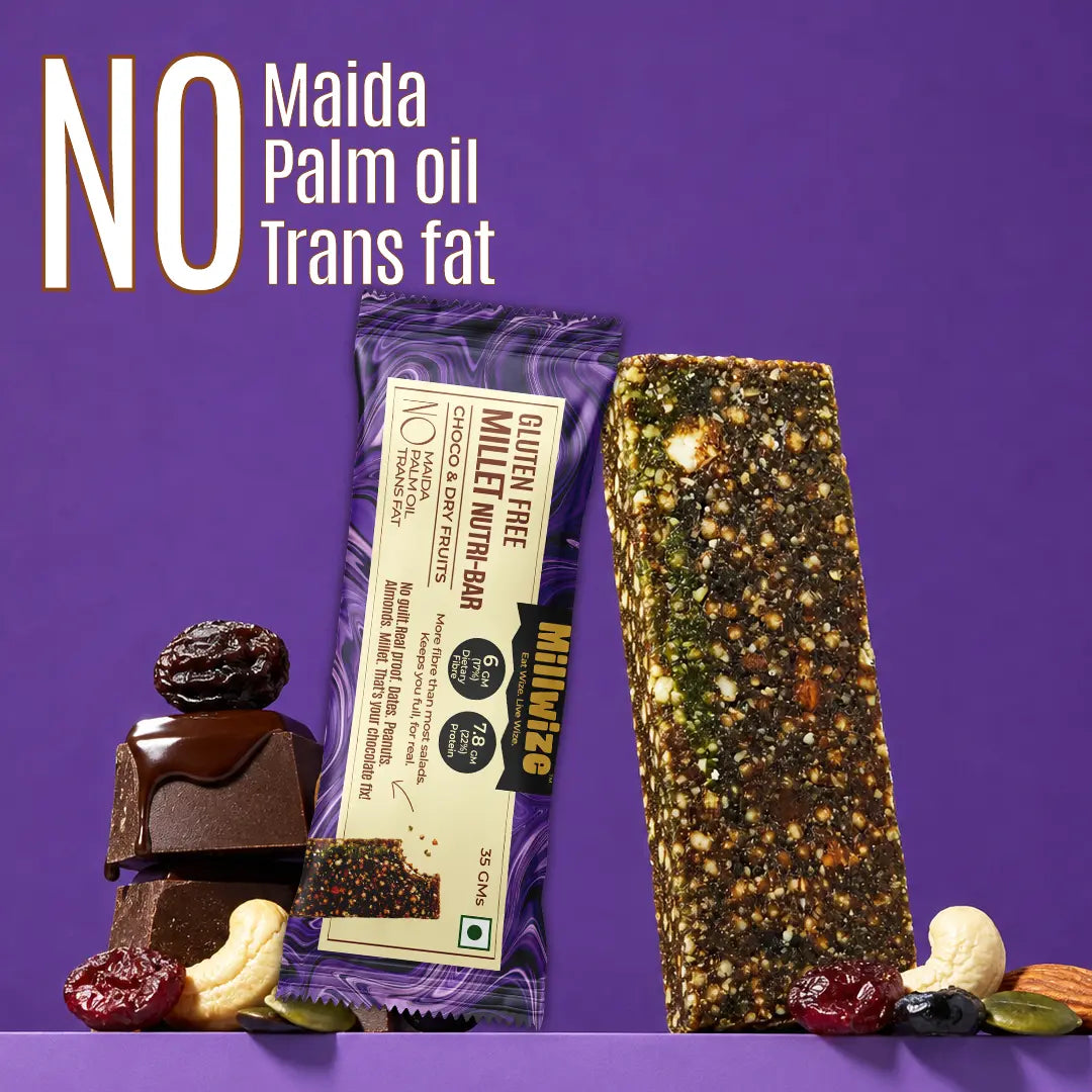 A packaged gluten free millet nut bar stands next to a loose, textured nut bar on a purple background, with stacked chocolate and dried fruit pieces at the base. Large text at the top reads 'NO Maida Palm oil Trans fat'.